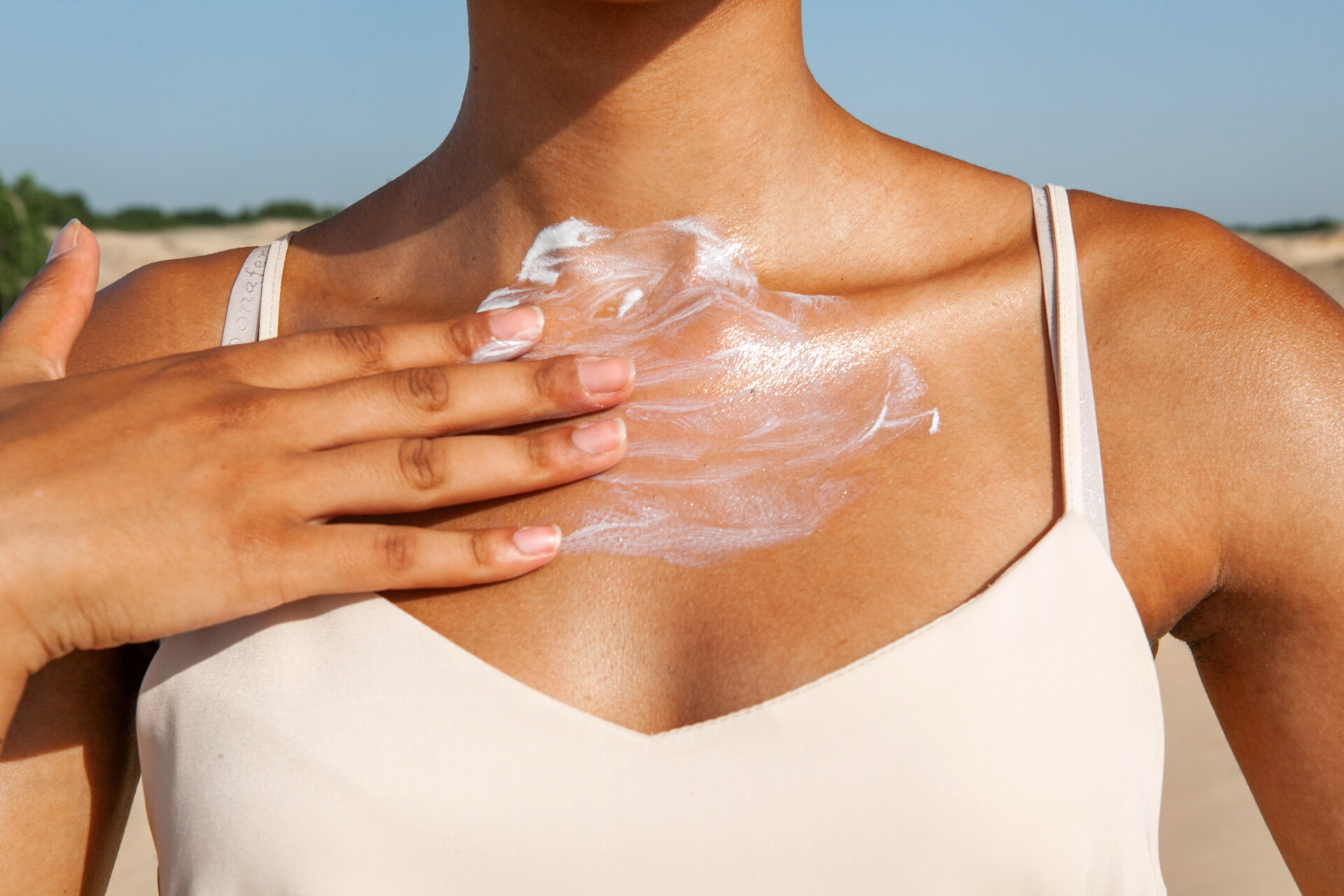Dark-skinned,Woman,Applying,White,Cream,To,Her,Chest,While,Standing